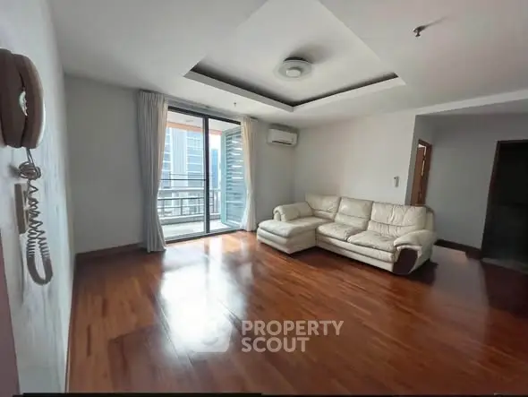 Spacious living room with hardwood floors and balcony access in modern apartment.