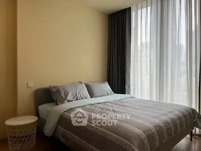 Cozy bedroom with modern decor and large window offering natural light