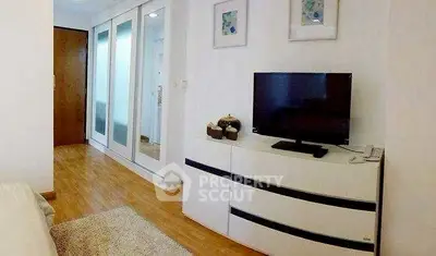 Modern bedroom with sleek TV unit and mirrored wardrobe doors.