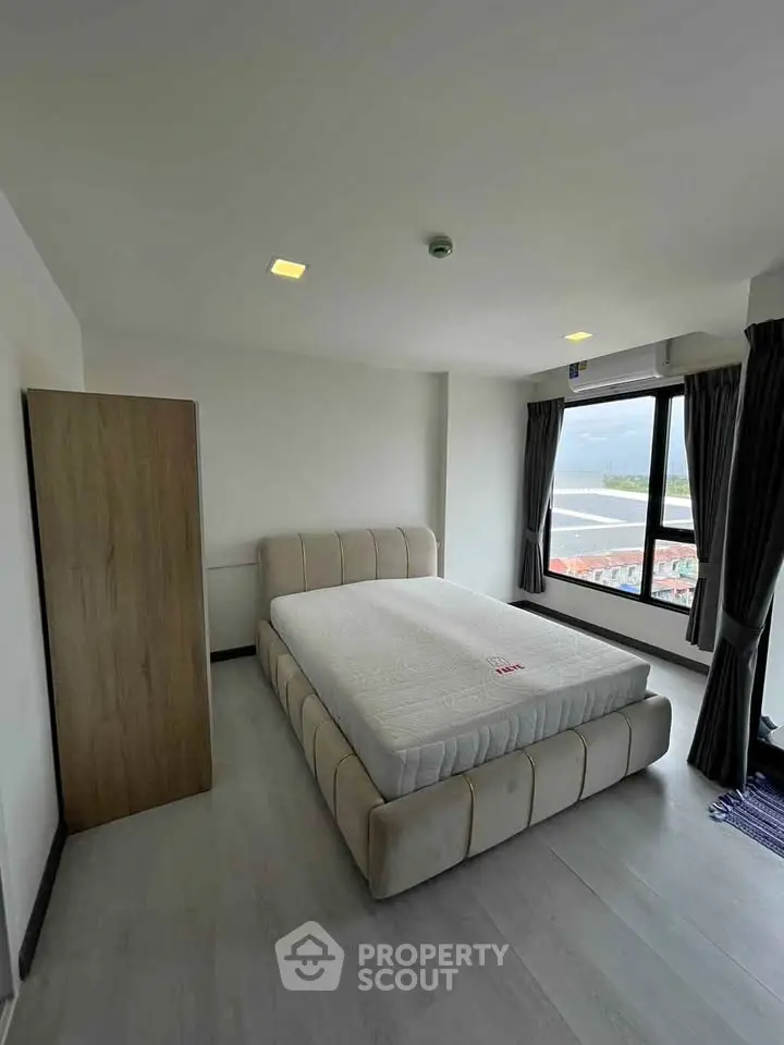 Spacious bedroom with large window offering stunning views, featuring a comfortable bed and modern decor.