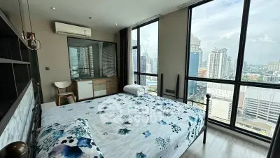 Modern bedroom with stunning city view and large windows in high-rise apartment.