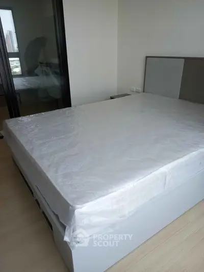 Modern bedroom with large bed and city view, perfect for urban living.