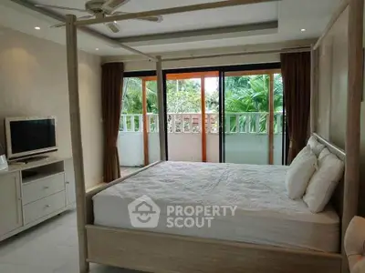Spacious bedroom with canopy bed and balcony view in tropical setting.