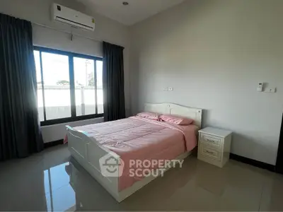 Spacious bedroom with large window and modern furnishings in a stylish home.
