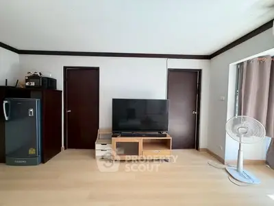 Spacious living room with modern TV setup and sleek wooden flooring