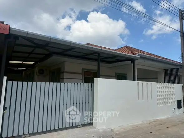Charming single-story home with modern fence and red-tiled roof under blue sky.
