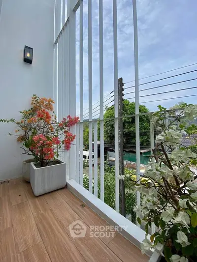 Charming balcony with potted flowers and scenic view, perfect for relaxation.