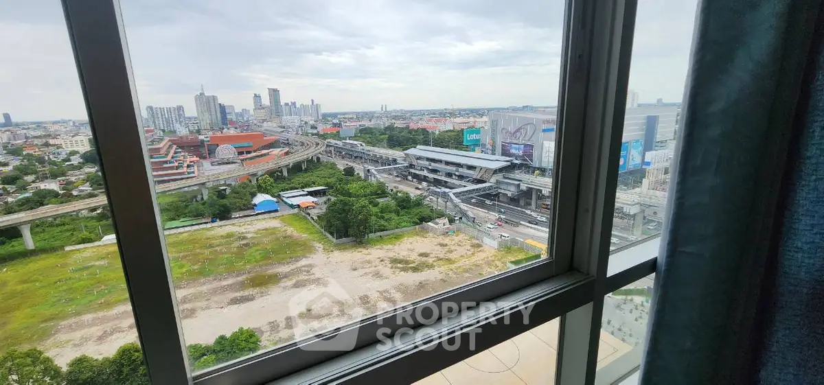 Stunning cityscape view from high-rise apartment window, showcasing urban skyline and transportation network.