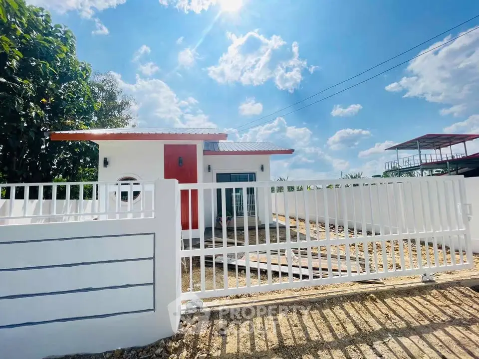 Charming modern house with white fence under a bright blue sky