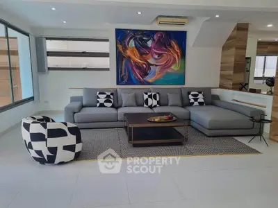 Modern living room with stylish sectional sofa and abstract art, featuring large windows and contemporary decor.