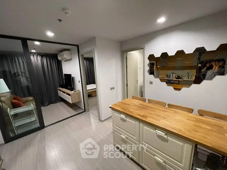 Modern apartment interior with open kitchen and cozy living area, featuring stylish decor and ample natural light.