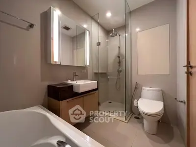 Modern bathroom with glass shower, bathtub, and sleek fixtures.