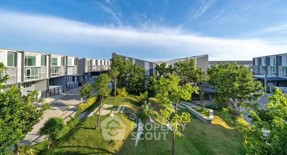 Modern townhouse complex with lush green landscaping and clear blue sky.