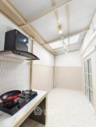 Modern kitchen with gas stove and sleek design, featuring ample natural light and stylish backsplash.
