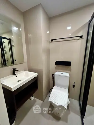 Modern bathroom with sleek fixtures and neutral tones, featuring a glass shower enclosure and contemporary vanity.