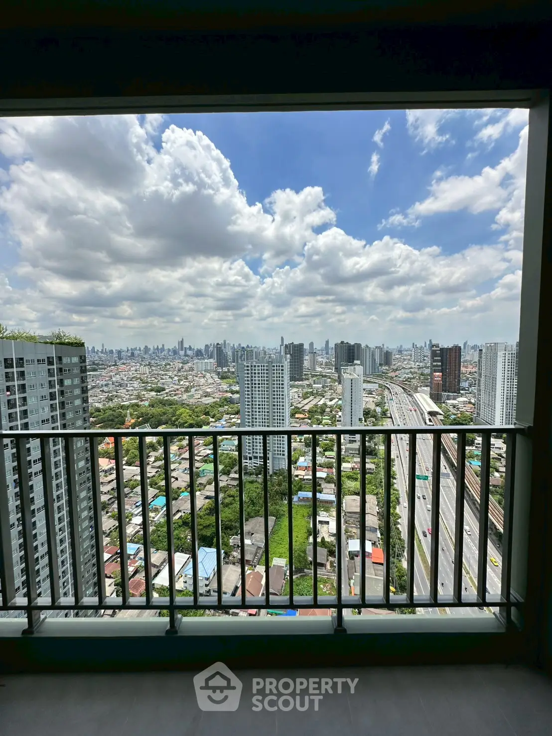 Stunning cityscape view from high-rise balcony with expansive skyline and highway.