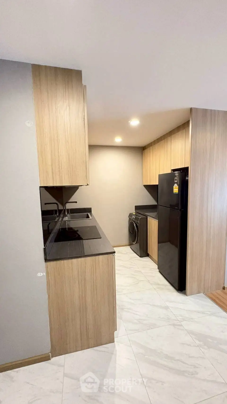 Modern kitchen with sleek wooden cabinets and black appliances in a cozy apartment.
