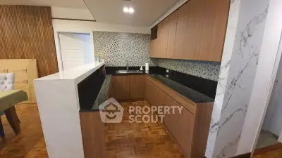 Modern kitchen with wood cabinetry and mosaic backsplash in open layout design.