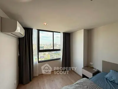 Spacious bedroom with city view and modern furnishings in high-rise apartment.