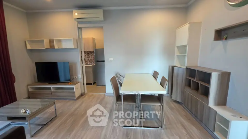 Modern living room with dining area and TV, featuring sleek furniture and neutral tones.