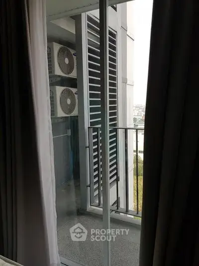 Modern apartment balcony with air conditioning units and city view.