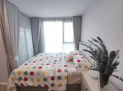 Cozy bedroom with polka dot bedding and elegant curtains, perfect for relaxation.