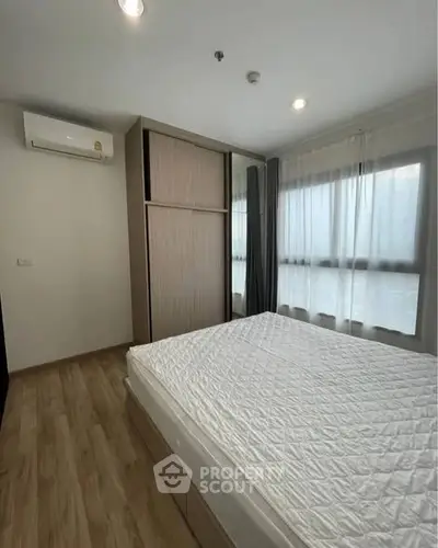 Modern bedroom with large windows and wooden flooring in a stylish apartment.