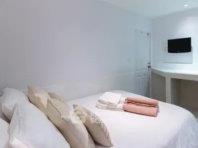 Cozy bedroom with modern decor and wall-mounted TV, perfect for relaxation.