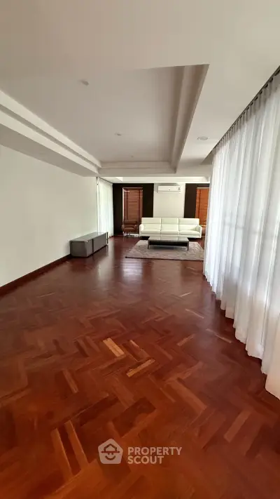 Spacious living room with elegant wooden flooring and modern white sofa.