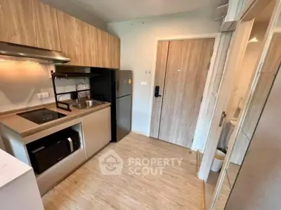 Modern compact kitchen with sleek wooden cabinets and built-in appliances in a cozy apartment.