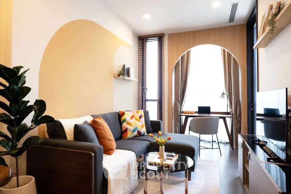 Modern living room with stylish decor and natural light, featuring a cozy sofa and workspace.