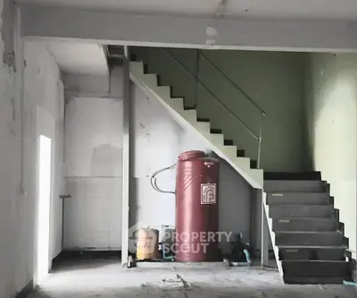 Industrial space with staircase and large water tank, ideal for storage or workshop use.