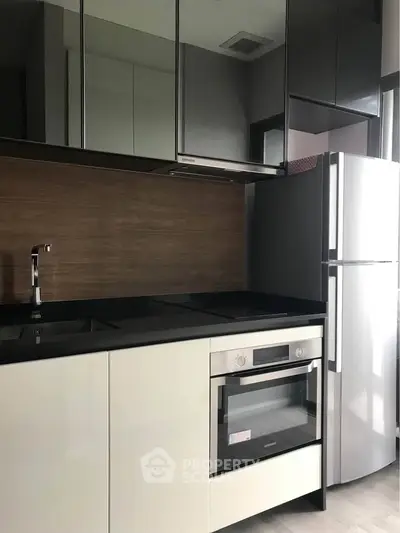 Modern kitchen with sleek cabinetry, built-in oven, and stainless steel fridge in a stylish apartment.