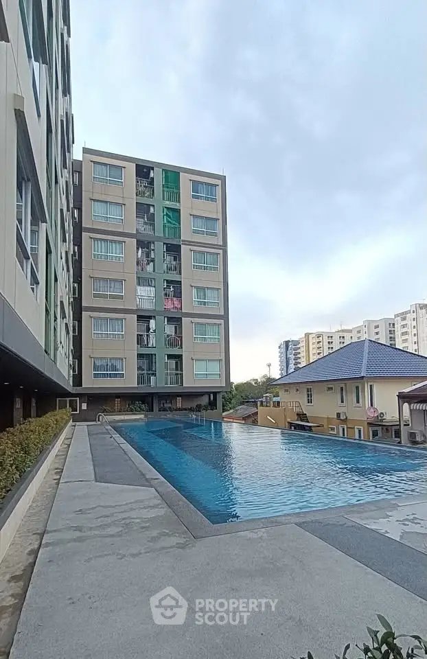Modern apartment building with a luxurious outdoor pool and spacious deck area.