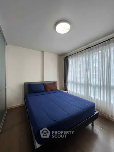 Cozy bedroom with modern decor and large windows for natural light.