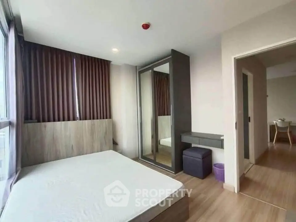 Modern bedroom with large window and mirrored wardrobe in stylish apartment.