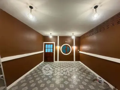 Spacious room with unique circular window and stylish lighting, perfect for creative interior design.