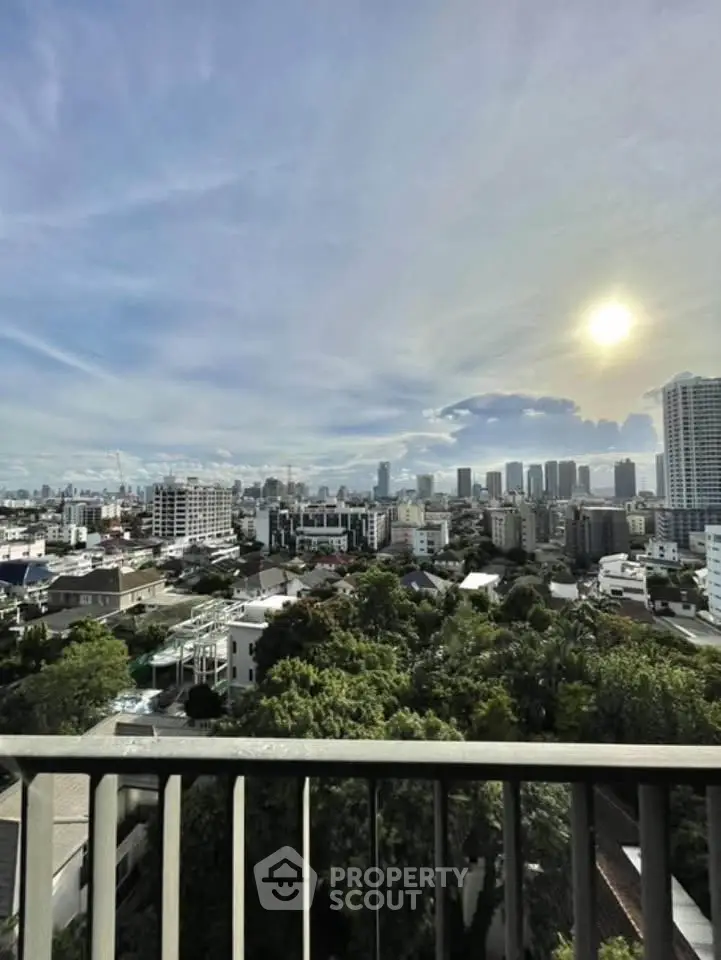 Stunning cityscape view from a high-rise balcony overlooking urban skyline and lush greenery.