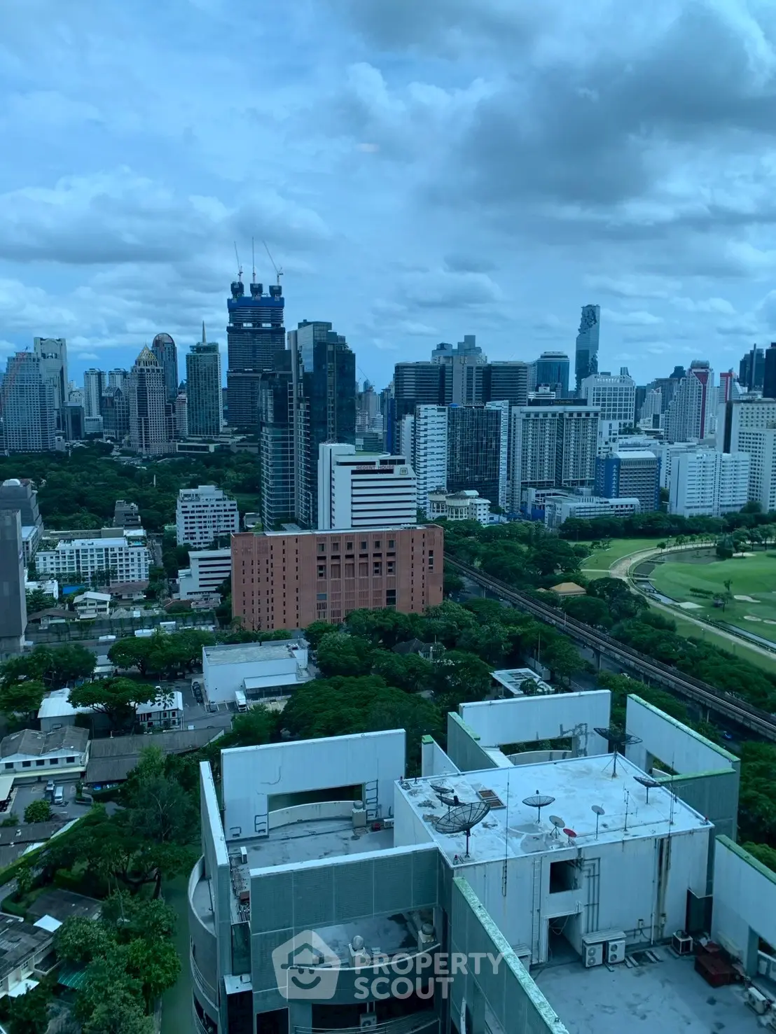Stunning cityscape view from high-rise building overlooking urban skyline and lush greenery.