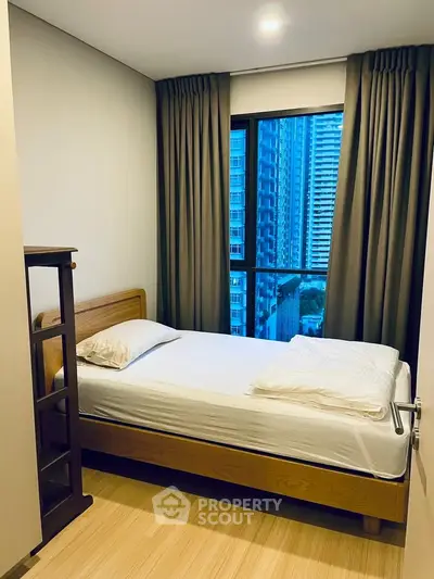 Cozy bedroom with city view, featuring a single bed and modern decor in a high-rise apartment.