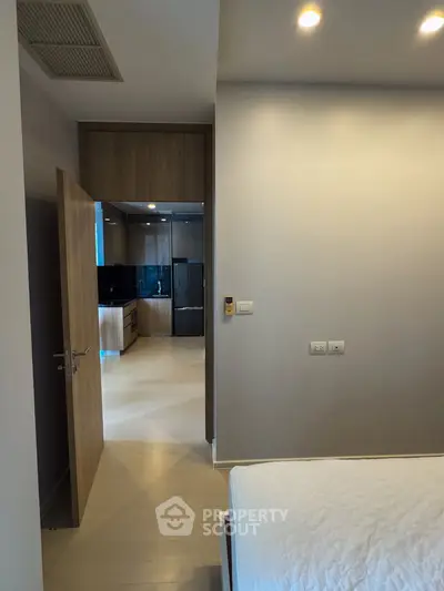 Modern bedroom with open door leading to sleek kitchen area