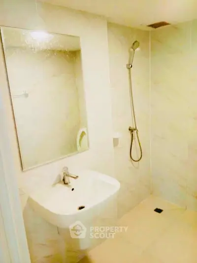 Modern bathroom with sleek sink and shower in a minimalist design.