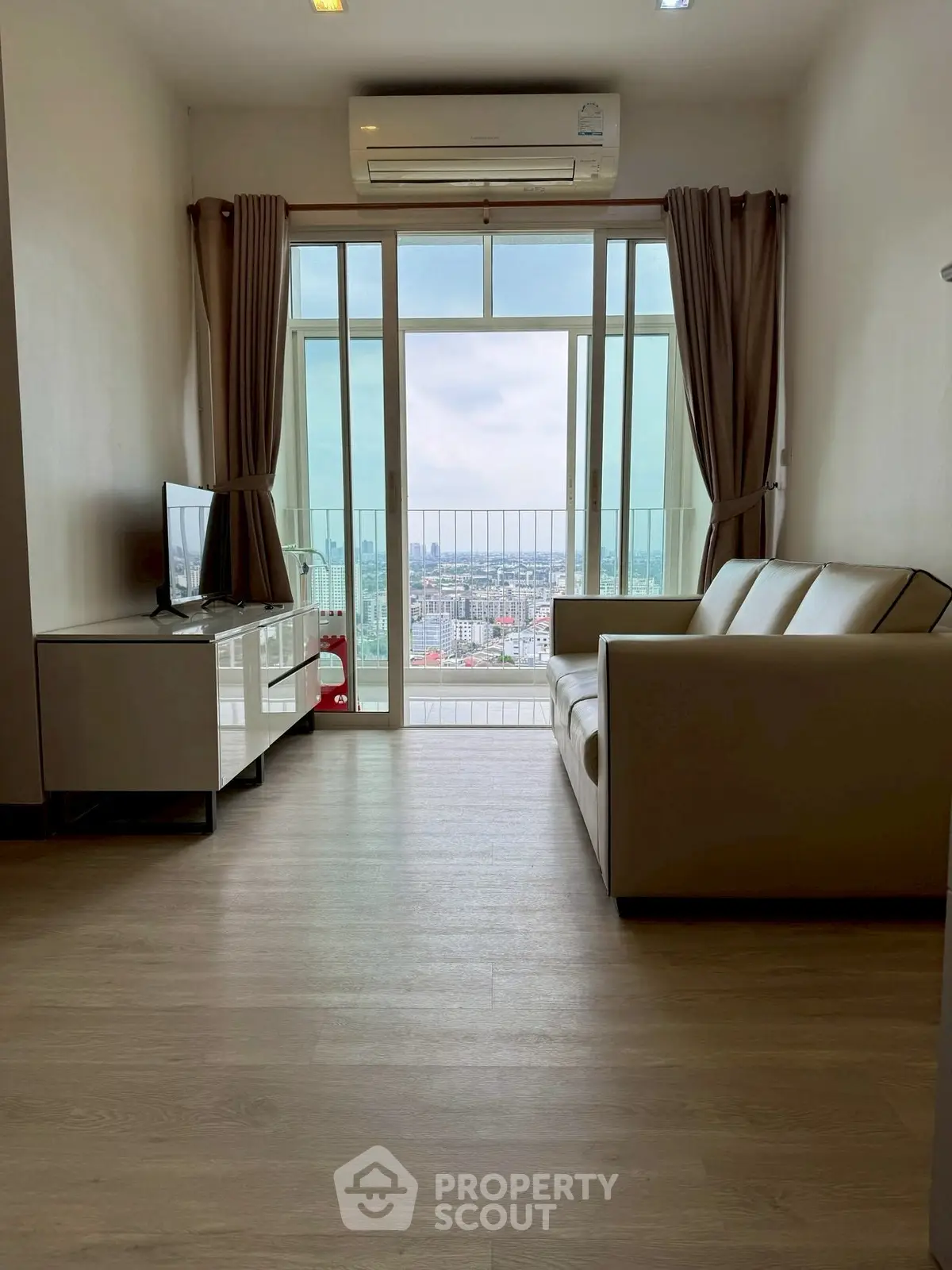 Modern living room with city view, featuring sleek furniture and large windows for natural light.