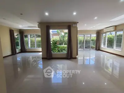 Spacious living room with large windows and garden view, perfect for natural light lovers.