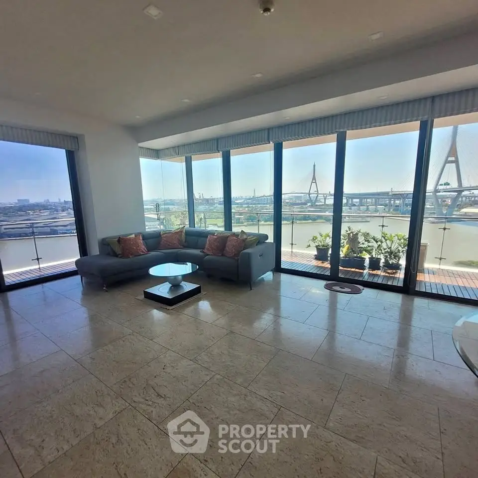 Spacious living room with panoramic river view and modern furnishings.