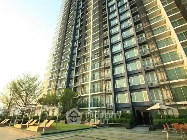 Modern high-rise building with lush garden and outdoor seating area