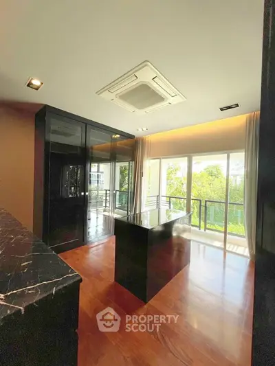 Luxurious modern kitchen with sleek black cabinetry and island, overlooking a lush green view.