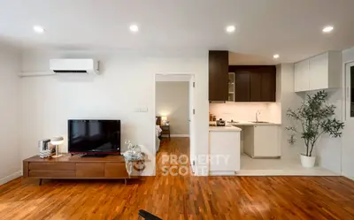 Modern open-plan living room with wooden floors and sleek kitchen design