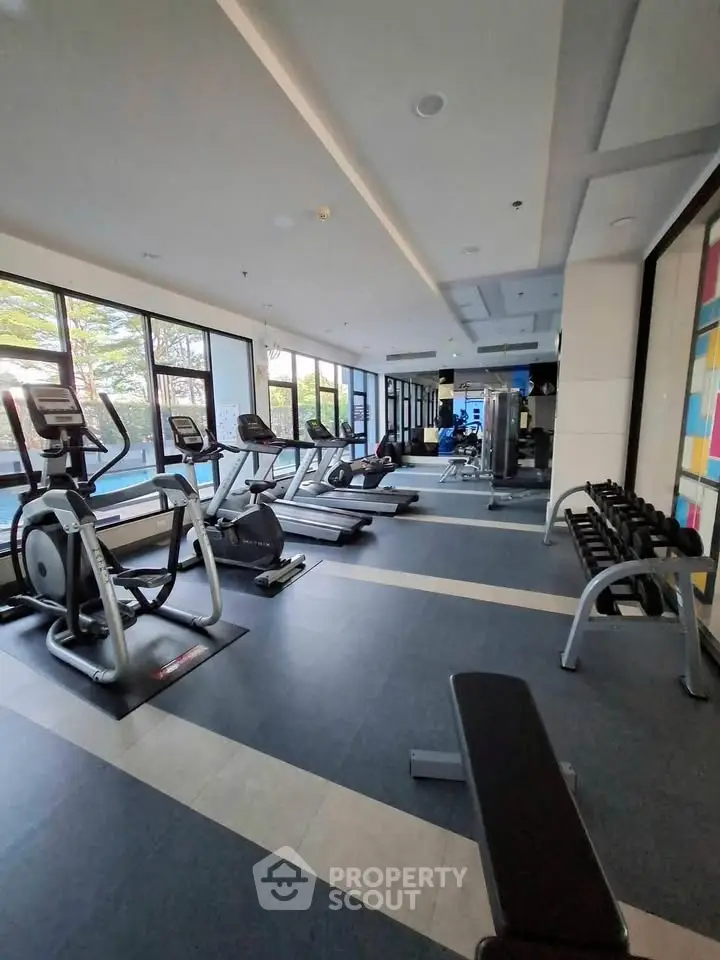 Modern gym with state-of-the-art equipment and large windows in a luxury residential building.