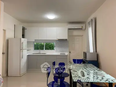 Modern kitchen with sleek white cabinets and dining area featuring blue chairs and glass table.